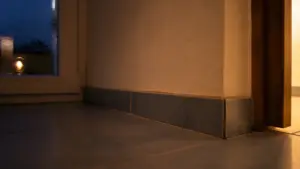 Dunkle Zimmerecke bei Nacht mit Sockelleiste und Fliesenboden im Streiflicht